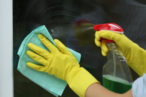 Female househlod,glass cleaning with rag and spray
